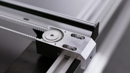 Close-up of a mechanical component with gears and metal parts on a gray background
